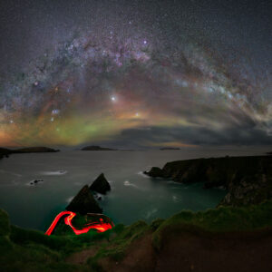 A mesmerizing long-exposure photograph of Dunquin Pier on the Dingle Peninsula, Ireland, featuring the glowing Winter Circle night sky and a dramatic coastal landscape.