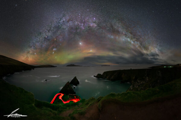 A mesmerizing long-exposure photograph of Dunquin Pier on the Dingle Peninsula, Ireland, featuring the glowing Winter Circle night sky and a dramatic coastal landscape.